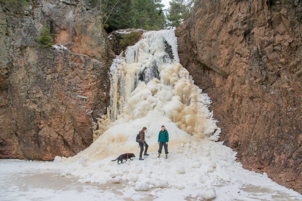 Picture of two explorers posing in front of a frozen waterfall.